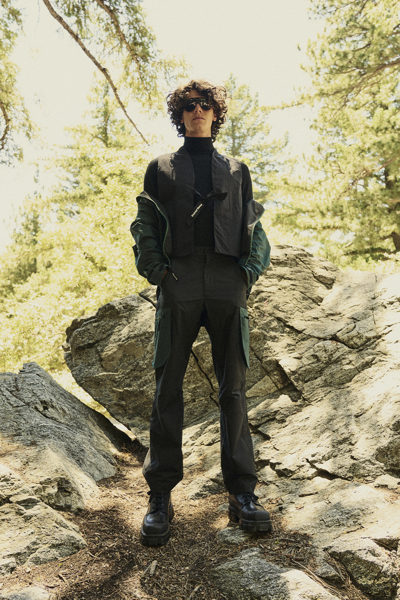 Man in black pants and jacket standing on a mountain hiking trail
