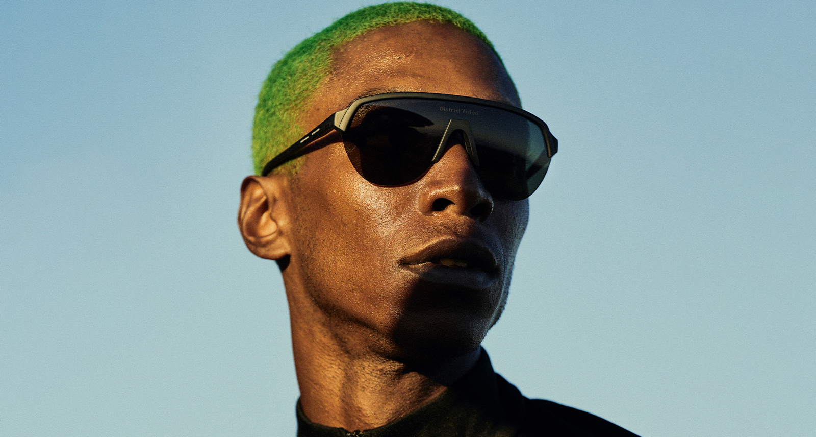 Man with green buzzcut wearing dark black sunglasses