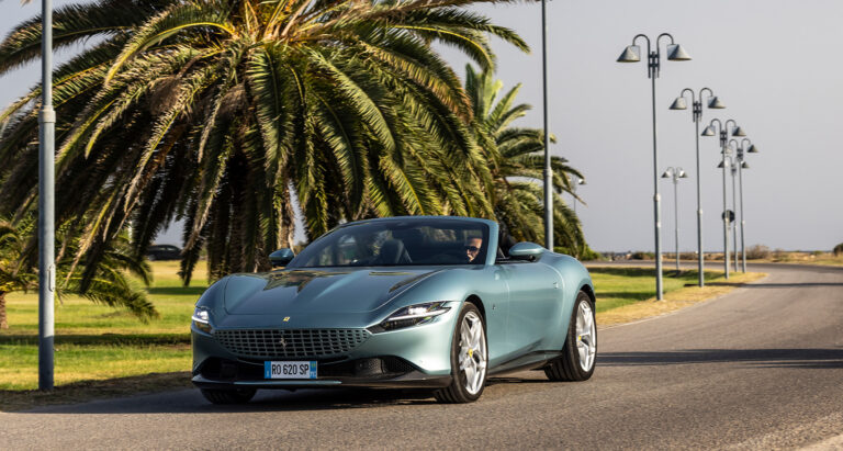 Ferrari Roma Spider parked beneath a palm tree in Sardinia