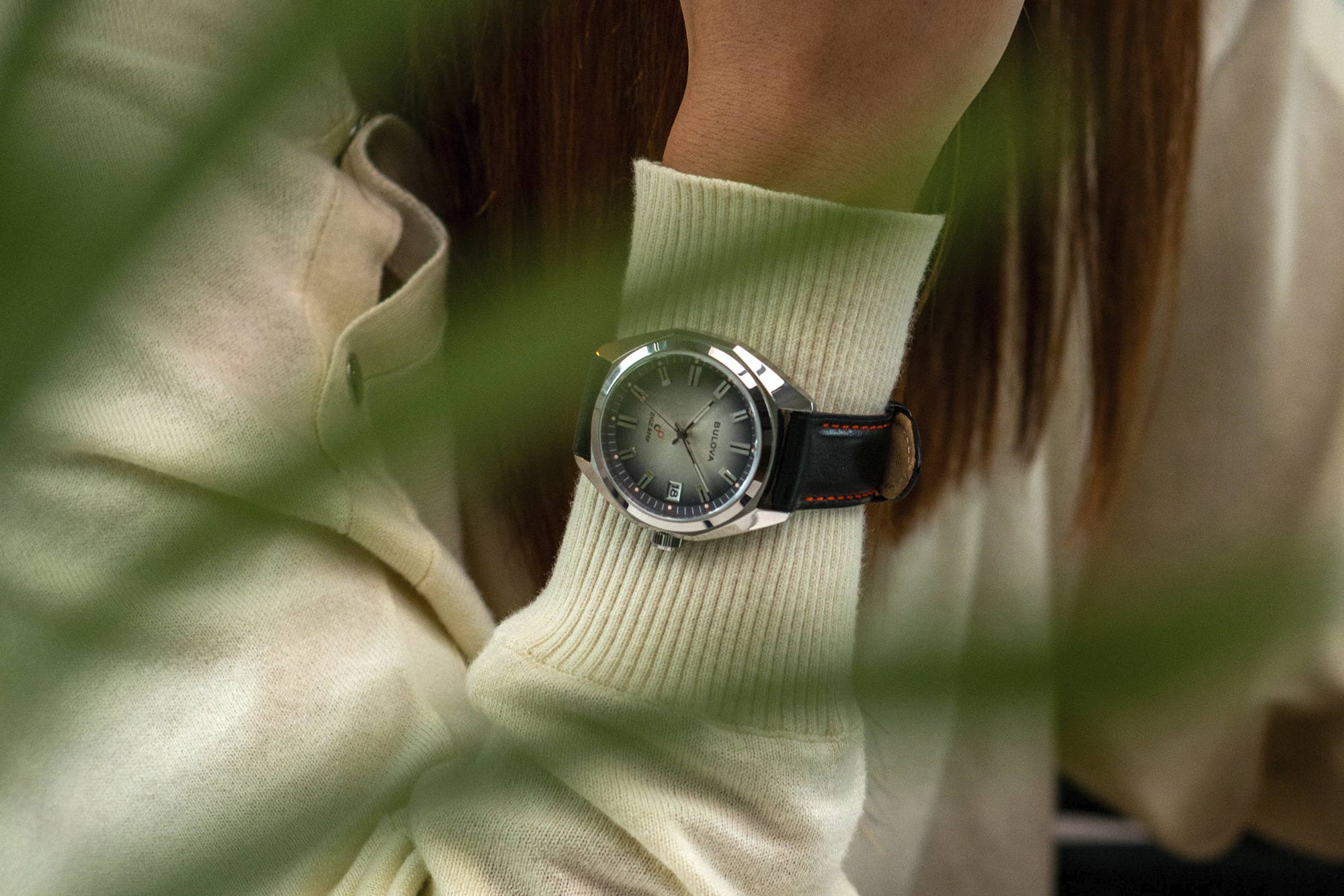 woman wearing bulova and complecto watch on her wrist, shot framed by palm frond