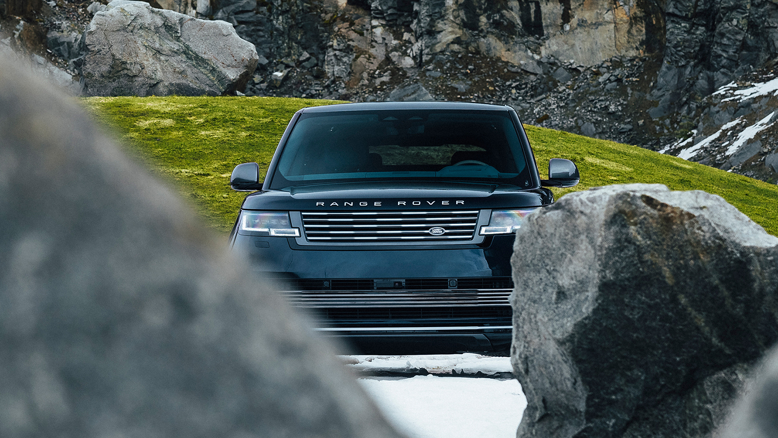 Range Rover Arete parked behind two boulders