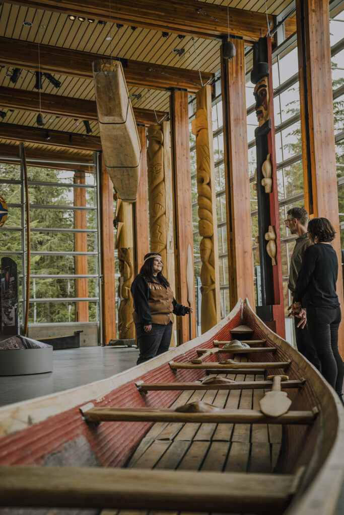at the Squamish Lil’wat Cultural Centre, people talk by a canoe