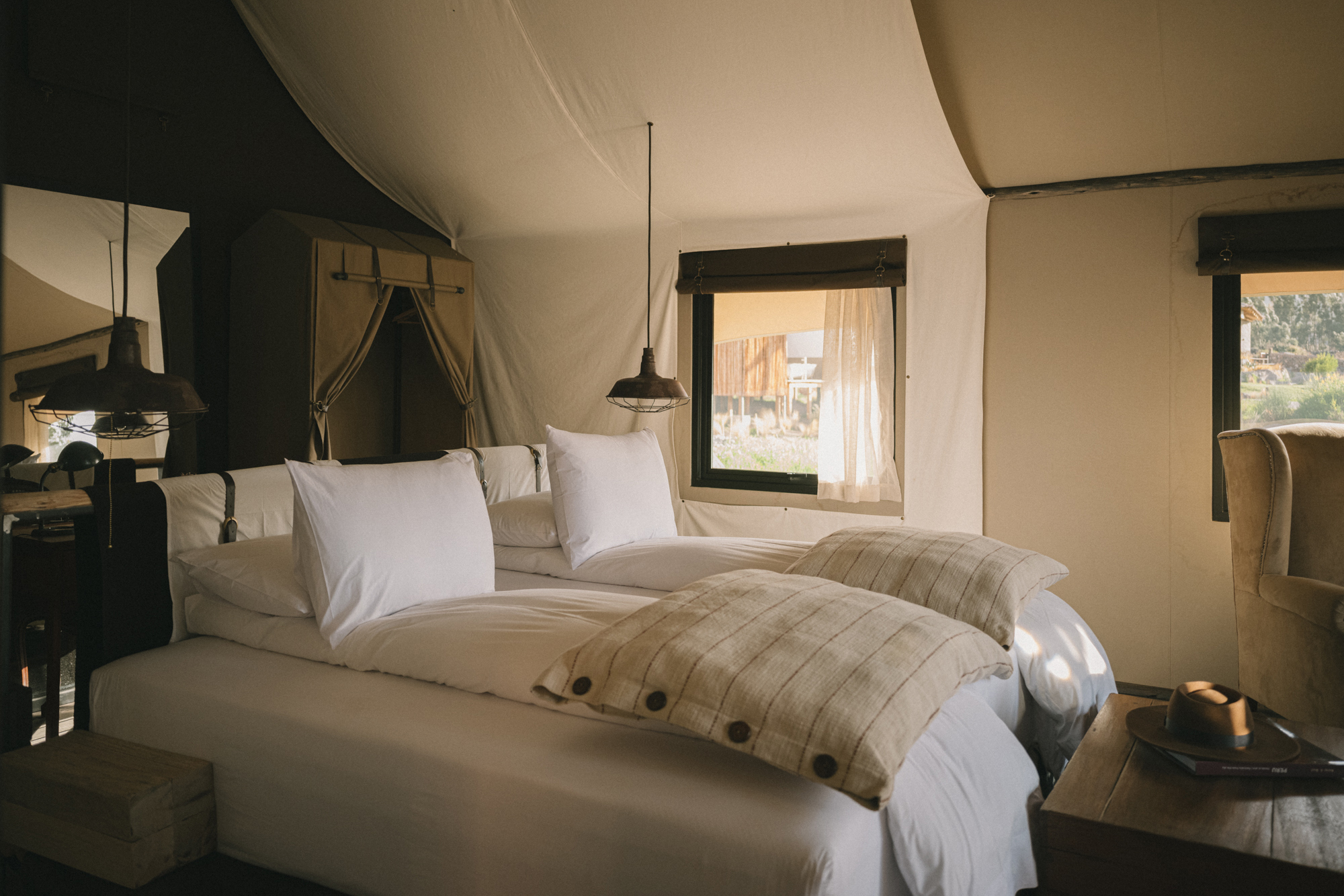 PUQIO Tented Resort in Southern Peru, photo shows large bedroom with white sheets and pillows