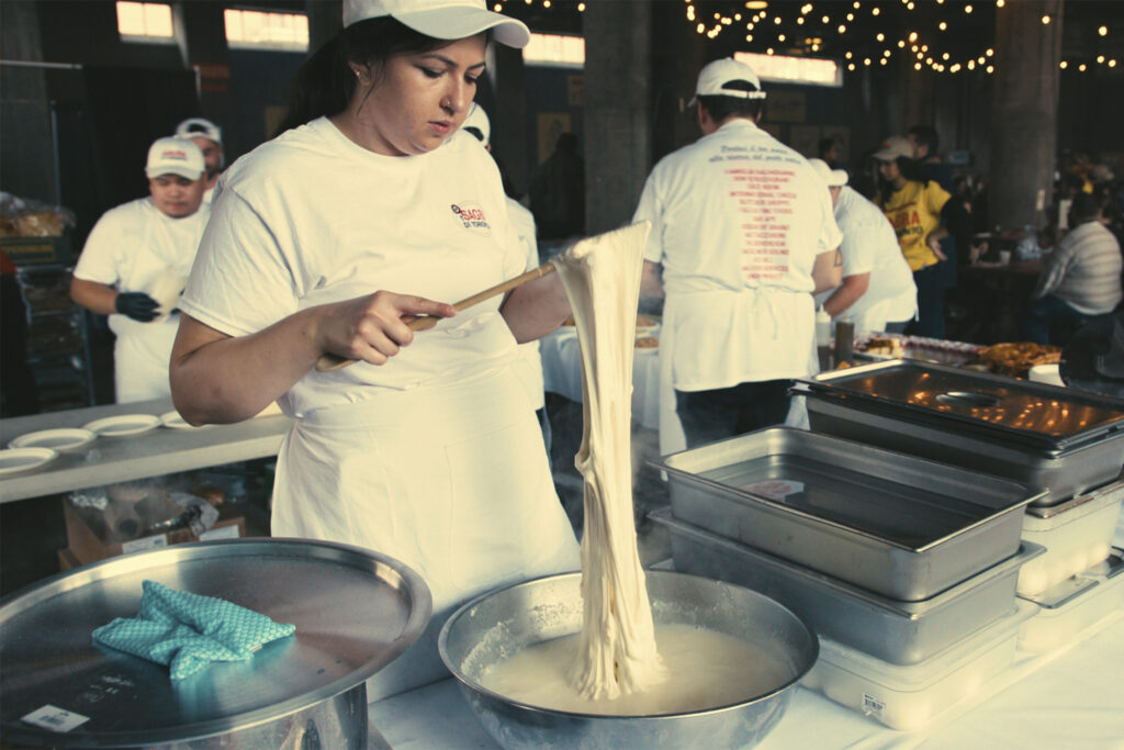 a chef stretches dough over a water bowl, preparing for the Sagra Di Toronto Food Festival 