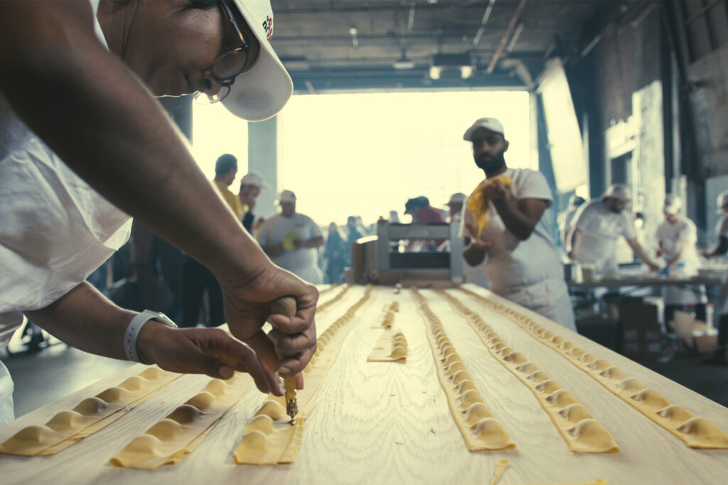 A man shapes pasta noodles on a table for Sagra di Toronto Food Festival.