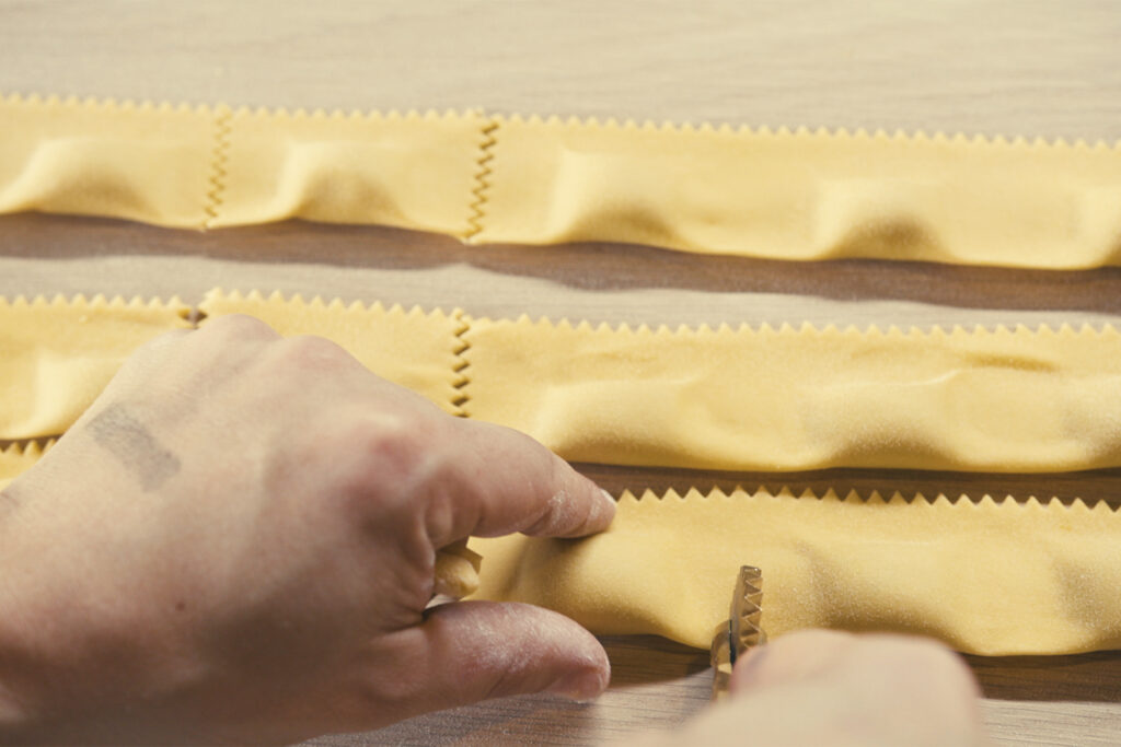 a close-up view of a hand cutting pasta dough ahead of the sagra di toronto festival 