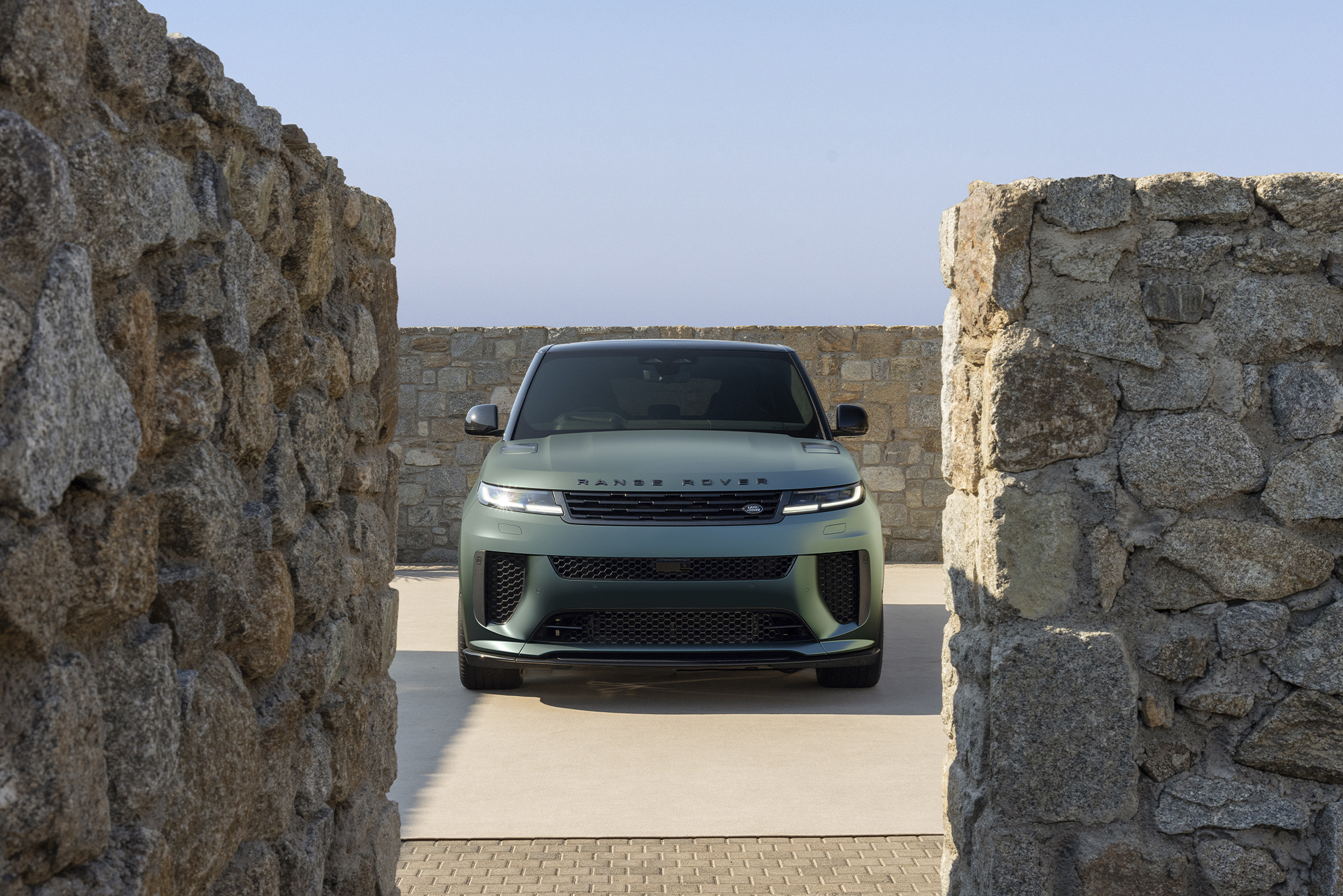 a range rover suv shot from the front, framed by rock walls