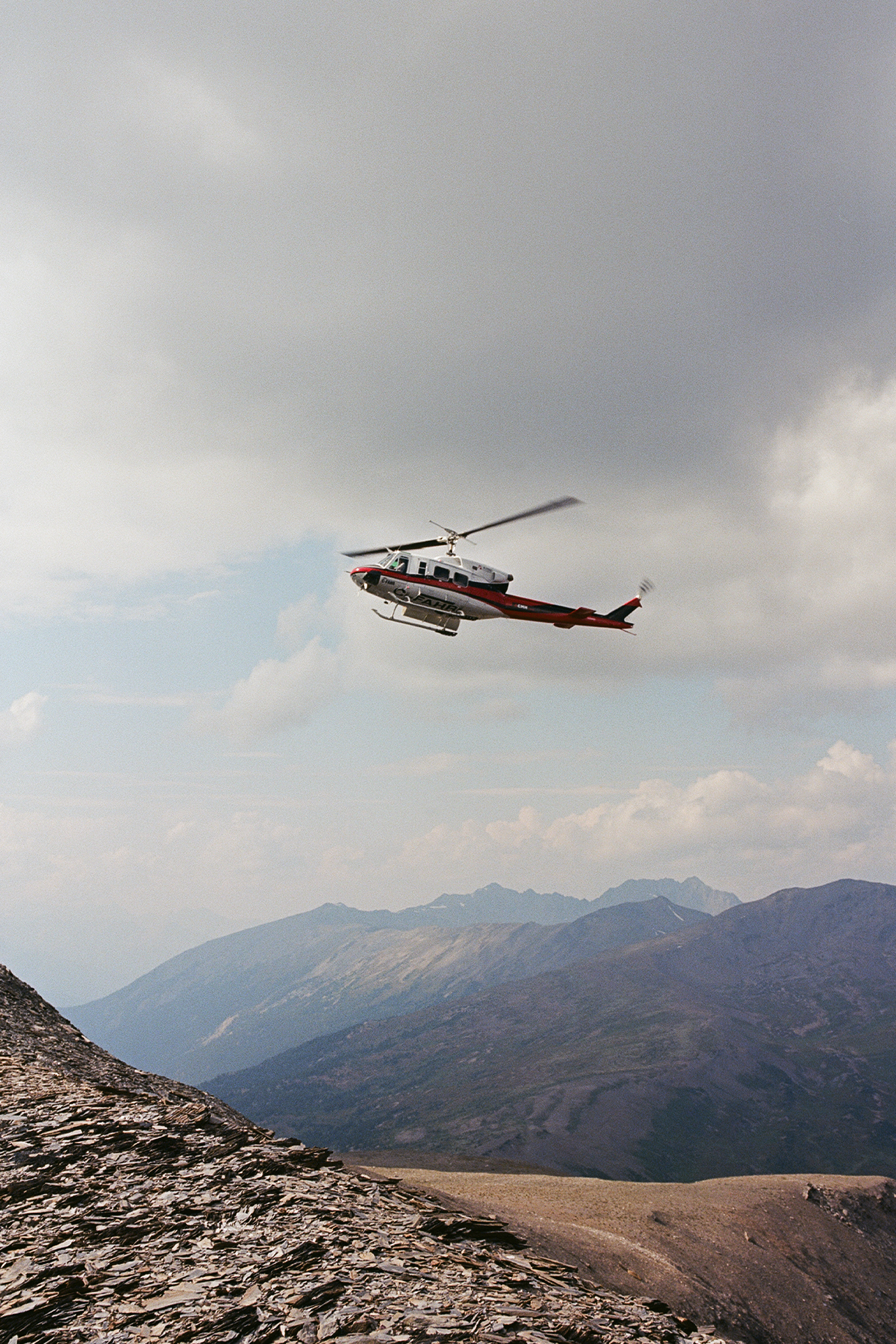 Trip to Alberta to celebrate Citizen Promaster 35-Year Anniversary. helicopter flies over mountain. grey skies