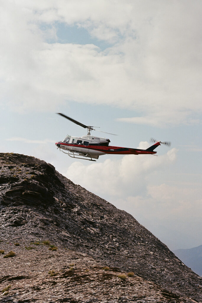 Trip to Alberta to celebrate Citizen Promaster 35-Year Anniversary. helicopter flies over mountain; the sky is cloudy