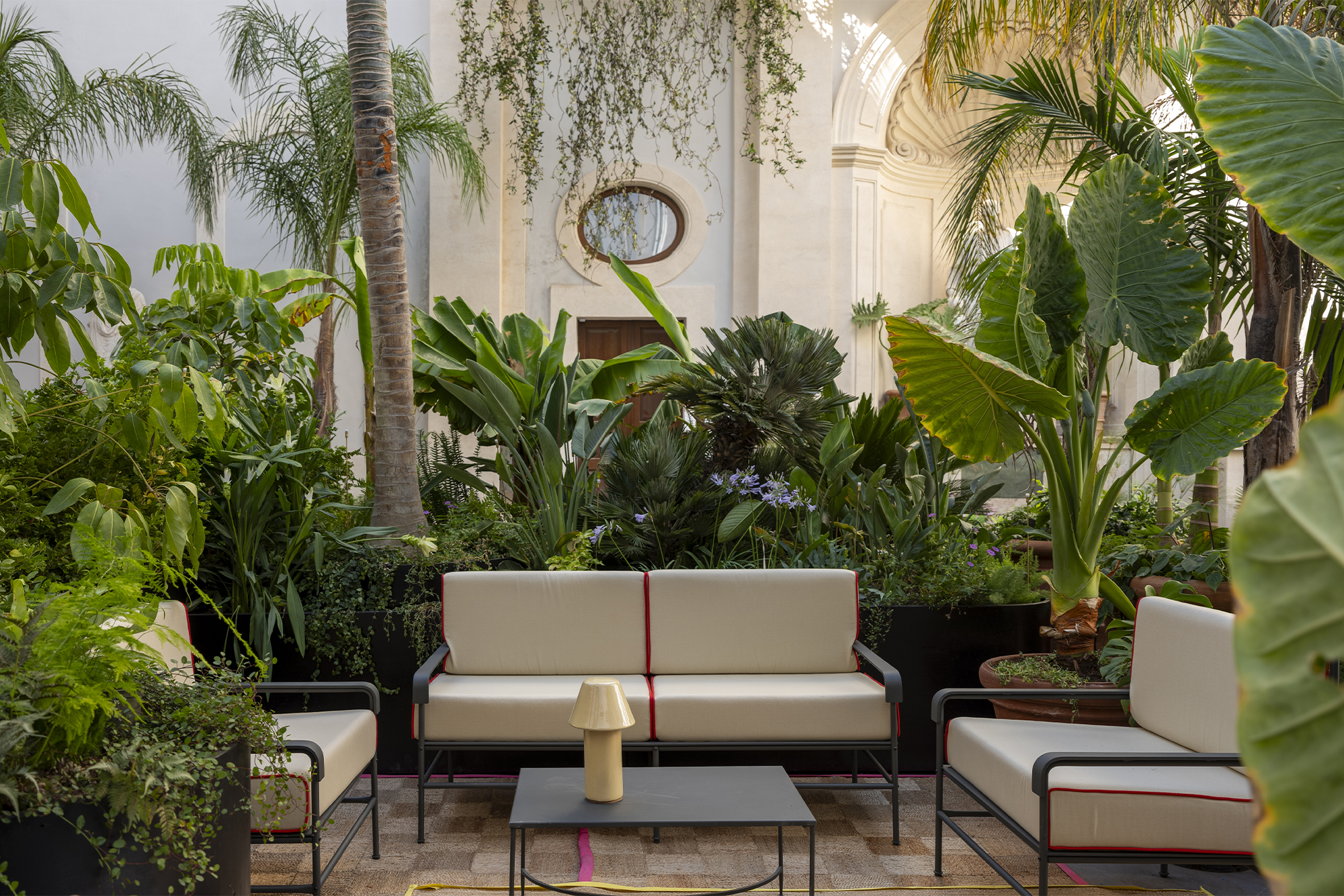 Palazzo Talia Roman Holiday exterior shot of garden patio area with greenery and white couches