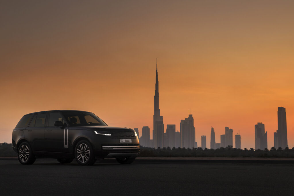 Range Rover Electric parked in front of a city skyline during sunset