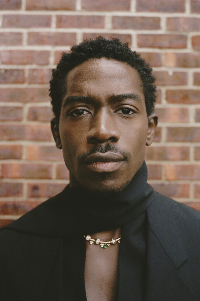 damson idris close-up by brick wall.