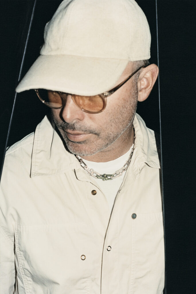 Daniel Arsham in white hat with orange glasses, looking down
