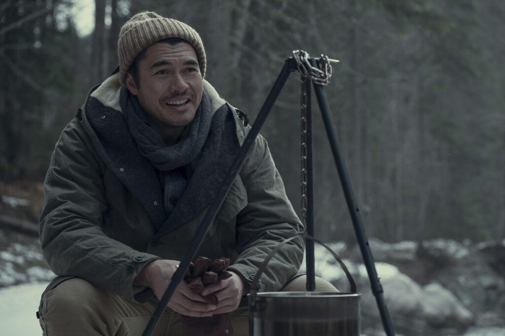 Henry Golding squats outdoors in the snow in still from Nine Perfect Strangers, courtesy of Prime Video.