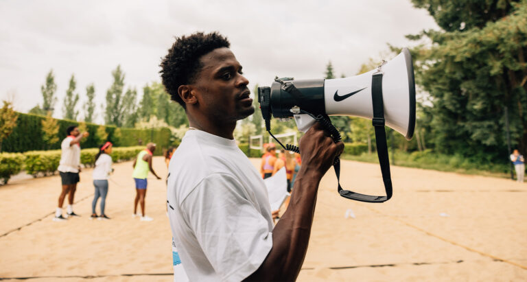 Joe Holder pictured from the side, holding a megaphone outside. Photo courtesy of Nike.