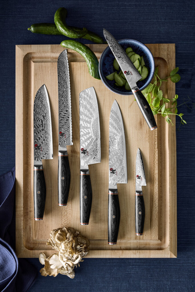 Miyabi Knives arranged on a cutting board of light wood.