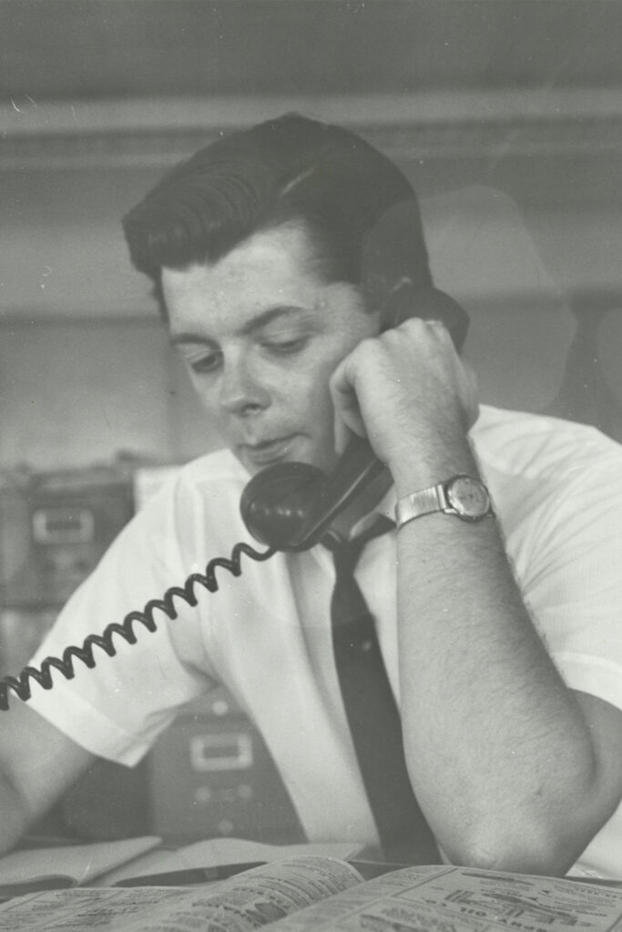 Photo courtesy of Brian Stewart, retrieved from SHARP September 2025. Brian Stewart new memoir, "On the Ground" shows a photo of stewart answering the phone at an Ottawa Newspaper.