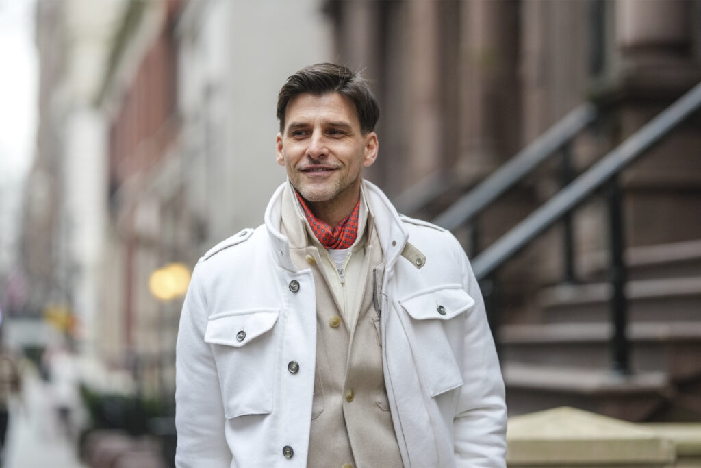 Johannes Huebl wears dark red scarf, white t-shirt, cream buttoned up shirt, white jacket, outside Todd Snyder, during the New York Fashion week Fall/Winter 2025 on February 6, 2025 in New York, New York. (Photo by Edward Berthelot/Getty Images)
