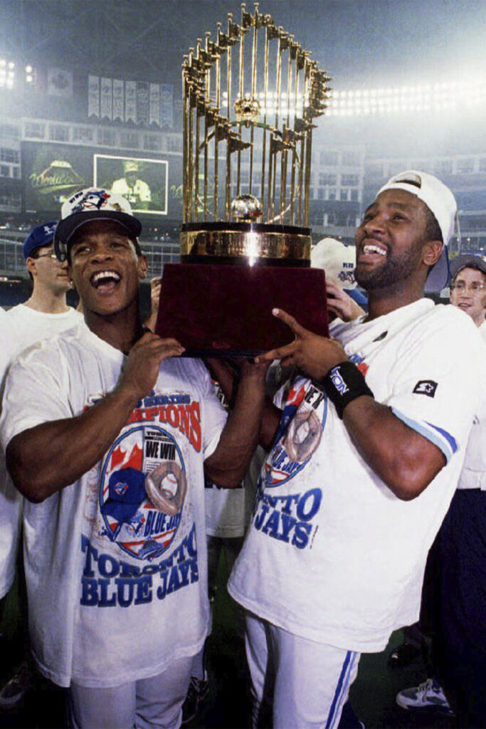 Toronto Blue Jays Rickey Henderson (L) and Joe Carter lift the World Series trophy for Blue Jays fans late 23 October 1993, in Ontario, Canada, after the Blue Jays won game six 8-6 over the Philadelphia Phillies and clinched the World Series. This is the second straight World Series victory for the Jays. (Photo credit should read CARLO ALLEGRI/AFP via Getty Images)