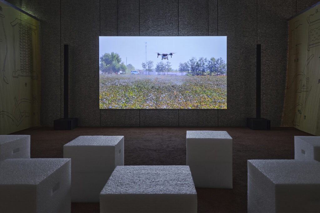 Exhibition view of “Dash” by Cao Fei Photo: Marta Marinotti and Federico Floriani Courtesy Fondazione Prada Cao Fei Super Farms, 2026 Mixed-media installation, variable dimensions A 47’13” single-channel documentary, photograph series, an earth-like environment, an organza curtain structure Structure of the installation developed by Small Production Courtesy of the Artis, Vitamin Creative Space and Sprüth Magers Work produced by Fondazione Prada on the occasion of the exhibition “Dash”